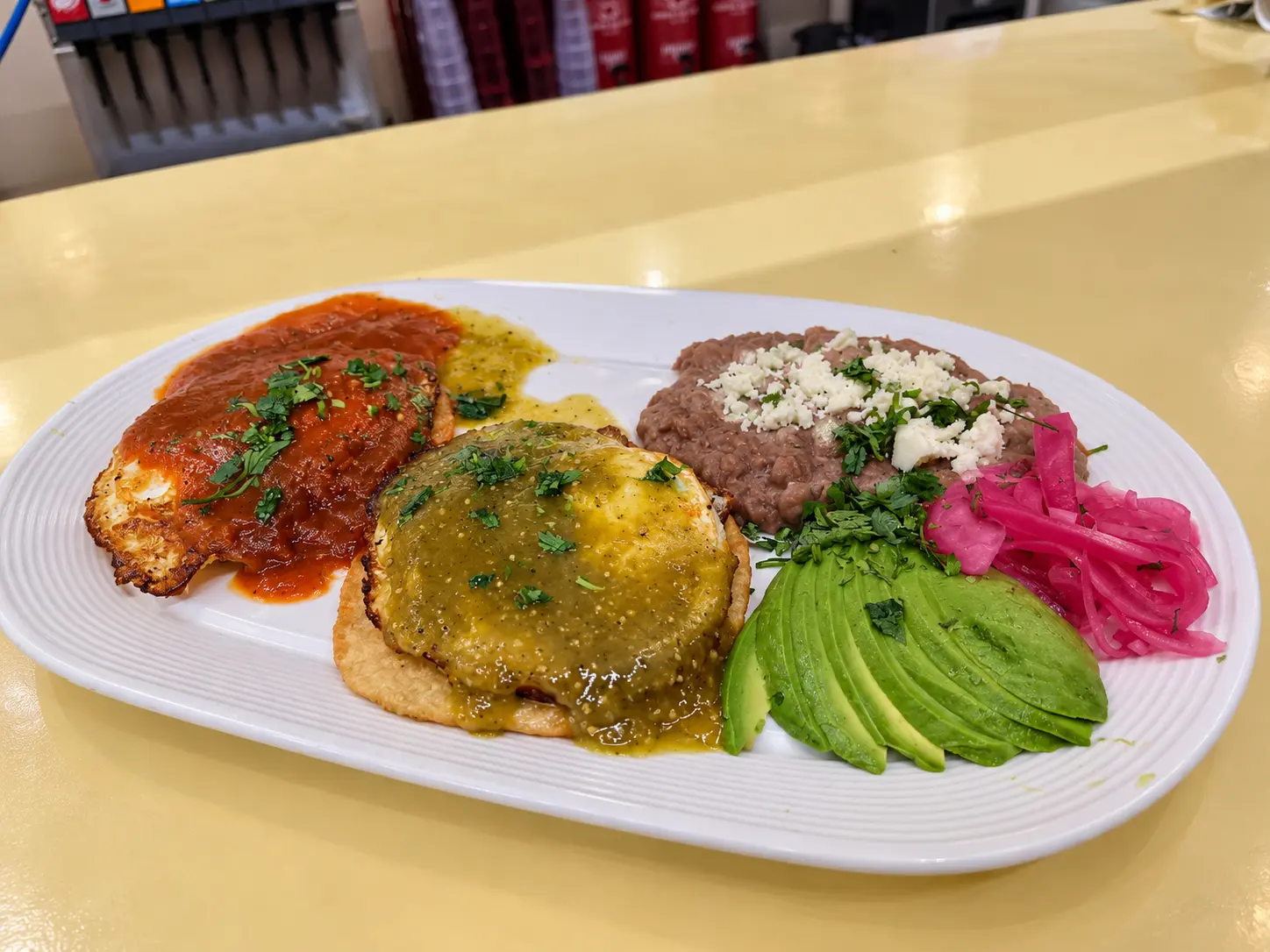 Eggs with red and green salsa, refried beans, avocado and pickled onions