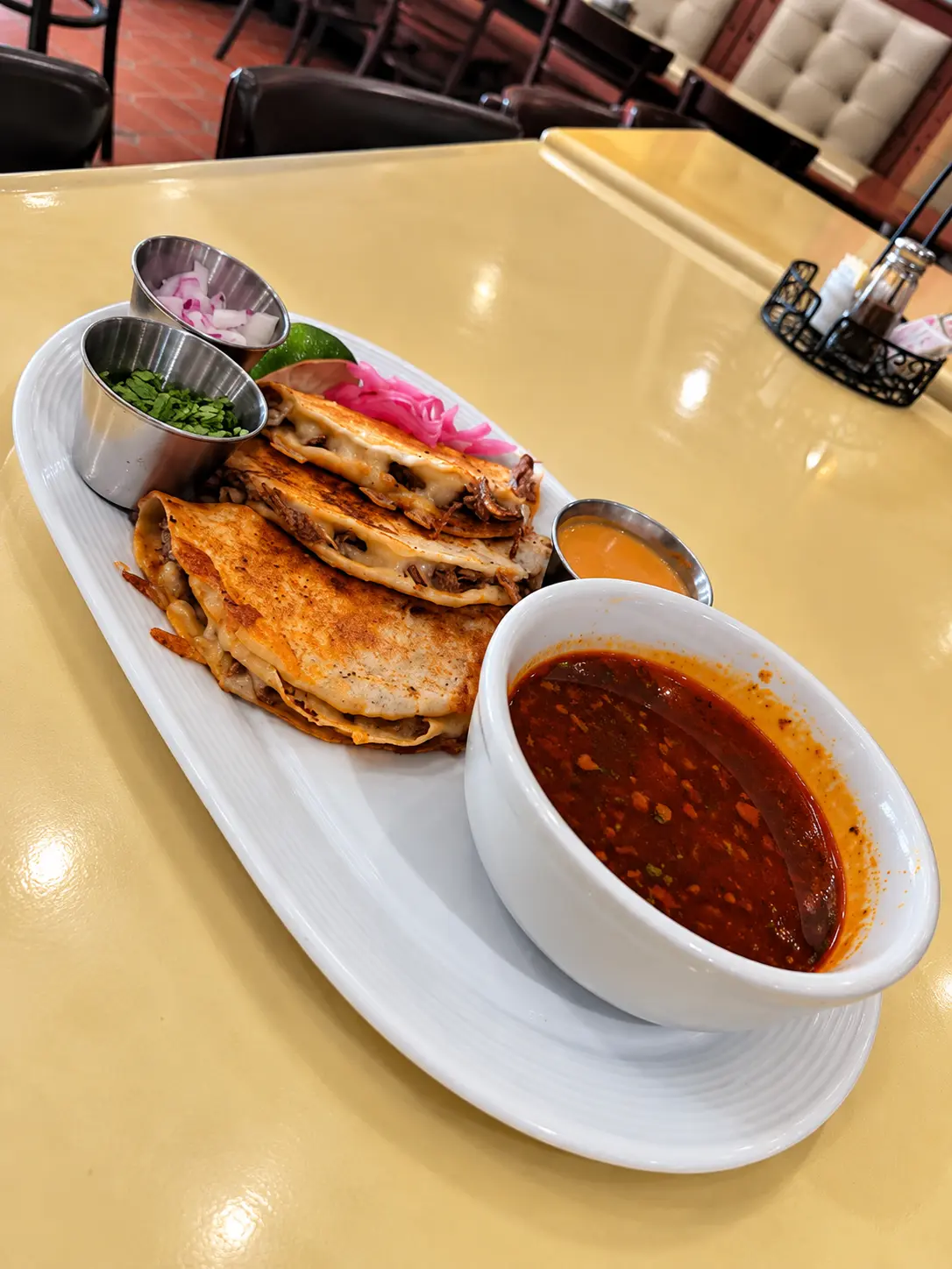 Birria tacos served with consommé, cilantro, onions and lime