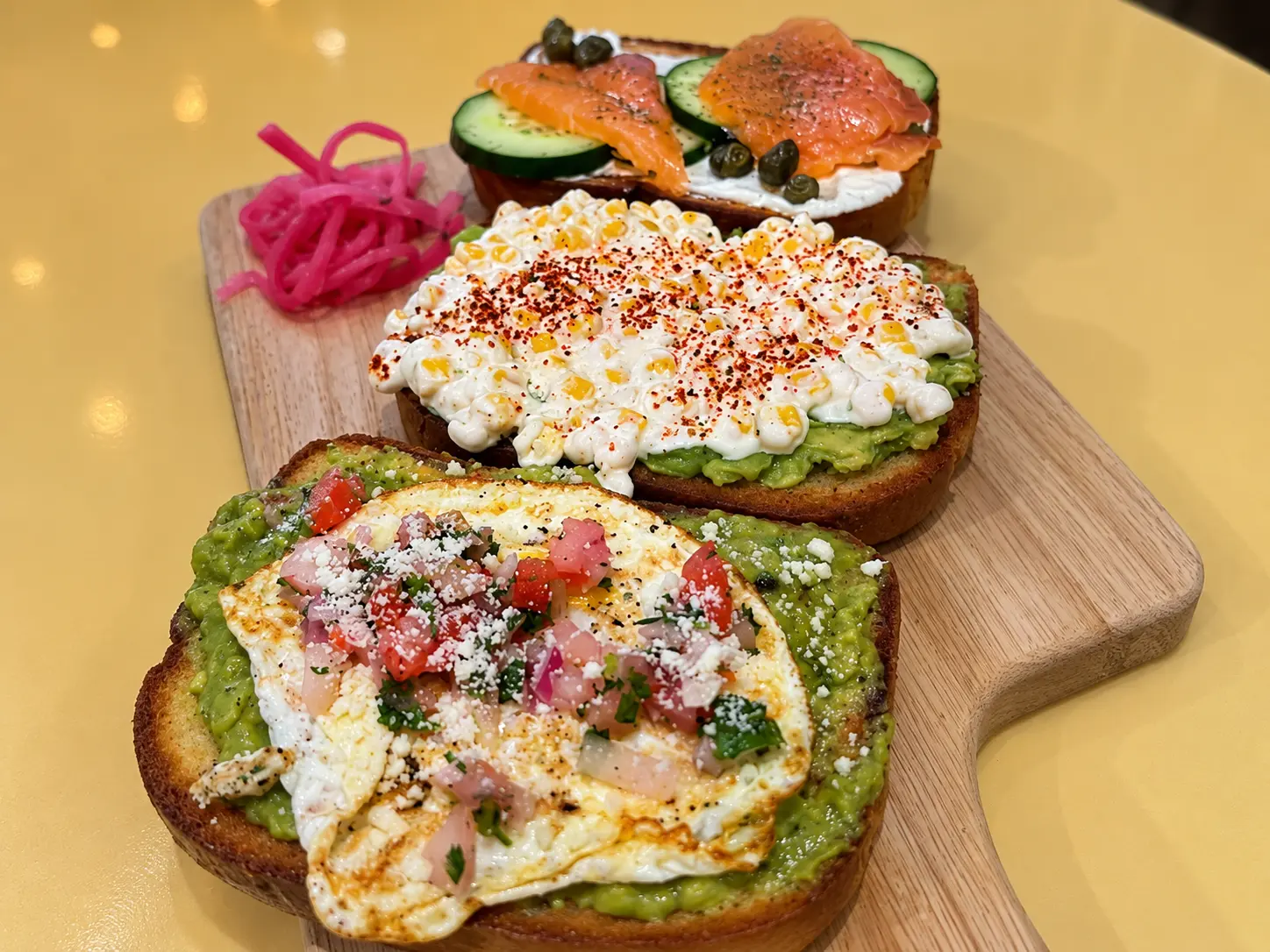 A trio of breakfast toasts with egg, corn and smoked salmon
